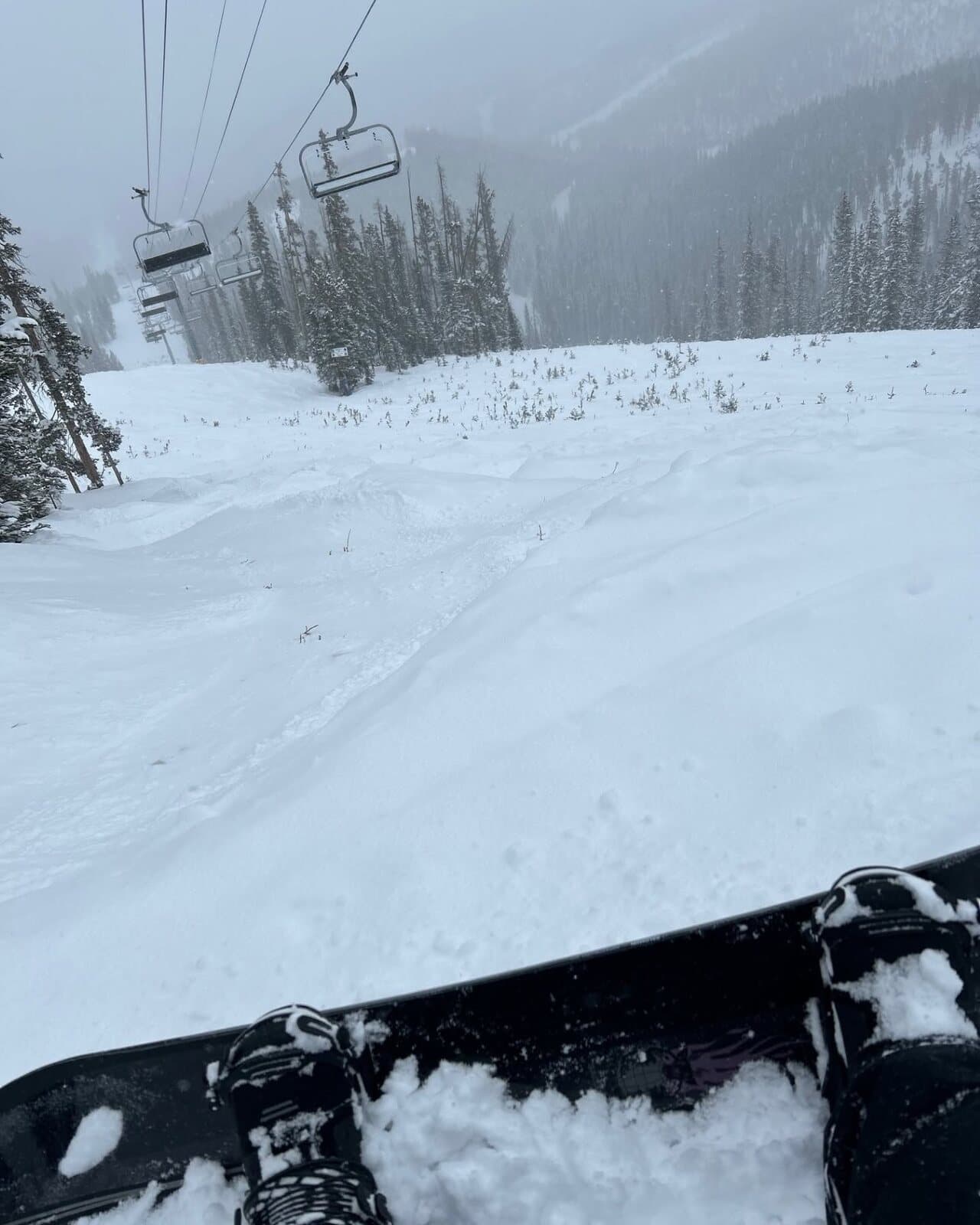 First-person view from a snowboard riding fresh powder under the lift